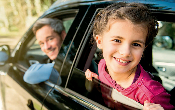 Padre e hija, en espacio de conductor y atrás, asomándose por la ventanilla de un auto