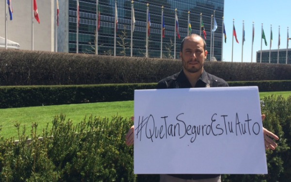 Stephan Brodziak con una pancarta que dice #QueTanSeguroEsTuAuto afuera de las instalaciones de la ONU en NY