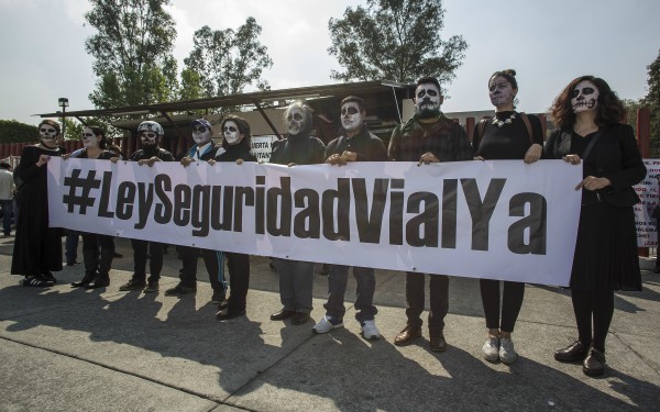 Activistas maquillados como calaveras desplegando una manta con la leyenda #LeySeguridadVialYa