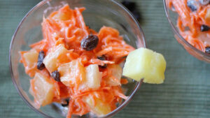 Ensalada de zanahoria, piña y pasas en un platón transparente visto desde arriba o cenital
