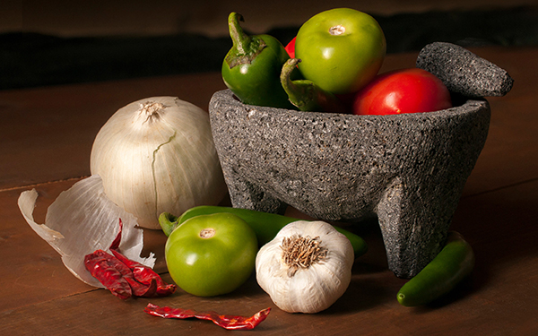 Molcajete en la mesa con ingredientes para hacer salsas mexicanas