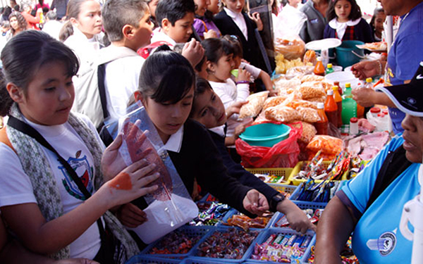 niños y niñas comprando alimentos chatarra afuera de la escuela