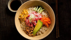 Poke bowl de arroz integral y pollo en un bowl sobre la mesa visto en picada o de manera cenital